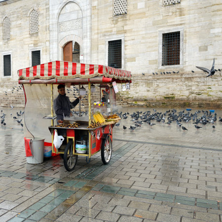 Istanbul, Turkey - December 10, 2023: Young man  seller of roasted chestnuts and corn in the cabin by the New Mosque and Egyptian Bazaarのeditorial素材