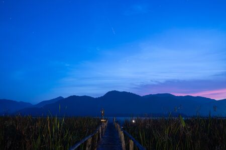 Stock Photo - Looking wood bridge and grass colorful sunrise on Mountainの写真素材
