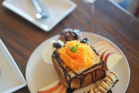 Honey toast toping golden egg strips with chocolate syrup and banana appleの写真素材