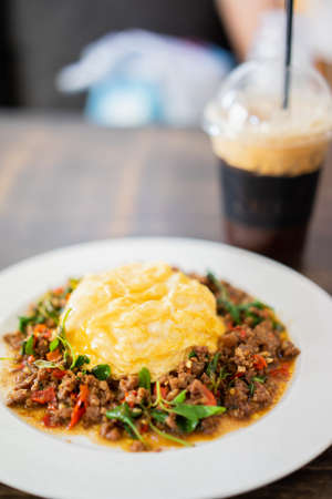 Beef with Basil top on rice and Scrambled eggs serve with Iced Americanoの写真素材