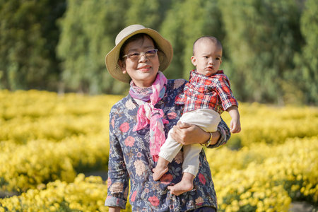 A cute baby boy with his grandmom spend time in a yellow flowers fields.の写真素材