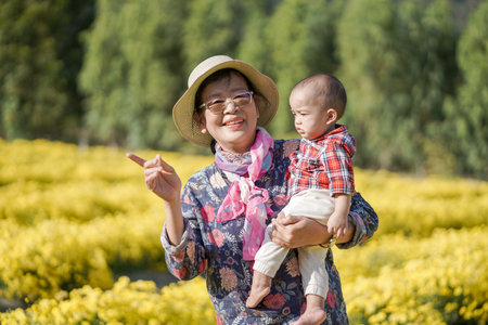 A cute baby boy with his grandmom spend time in a yellow flowers fields.の写真素材