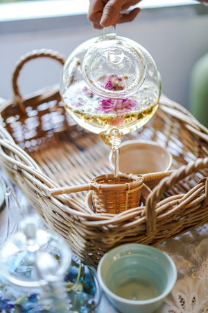 Beautiful indoor scene were hand is holding Herbal tea pot and pouring Herbal tea on the cup.の写真素材