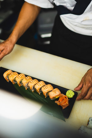 Chef preparing salmon rolls with precision and care. Perfect for food and cooking content. Fresh salmon and avocado rolls arranged on a plate. Ideal for food.の写真素材