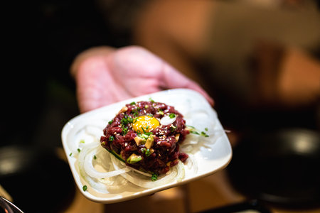 Yukke - Japanese Beef Tartare on hand selective focus blur background.の写真素材
