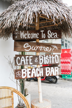 Sign at cafe, sign at sea, signpost, signboard, sea, beach, sky, city.の写真素材