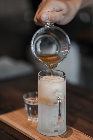 The barista pours coffee into a glass with ice.の写真素材