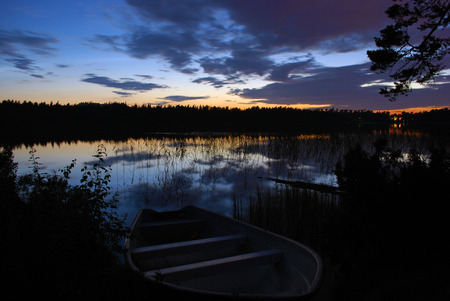Lake at night with a boat on the banksの写真素材