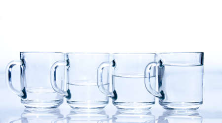 four blue cups filled with water unevenlyの写真素材