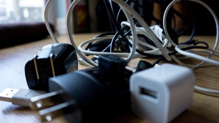 Smartphone tangled in differnt cables chargers usb and black and white wires