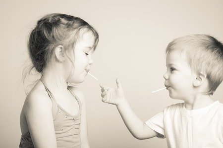 black and white photo of siblings playing with each others lollipopsの写真素材