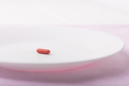 Miracle diet pill on a white plate, shallow depth of fieldの写真素材