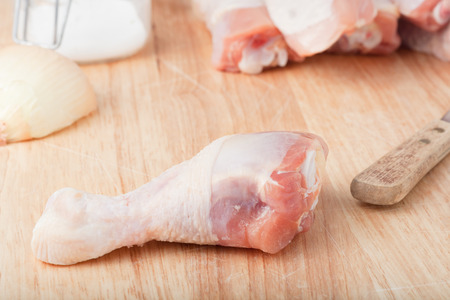 uncooked chicken legs on wooden chopping boardの写真素材