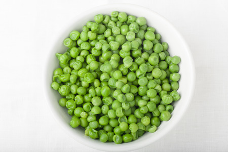 a bowl of cooked green peas on white background, top viewの写真素材