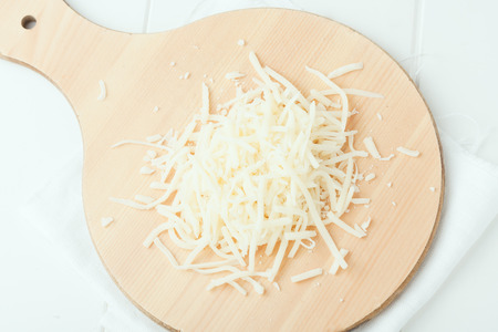 grated  cheese on round wooden chopping board, top viewの写真素材