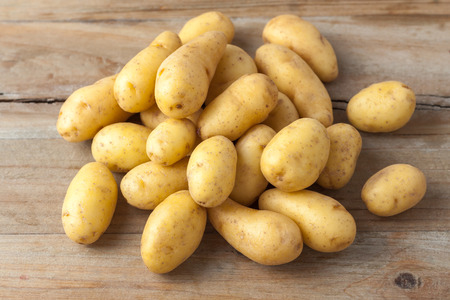 raw baby potatos on rustic wooden background raw baby potatos on rustic wooden background
