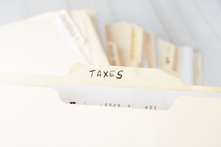yellow paper folder labeled TAXES containing tax documents of a small business firmの写真素材