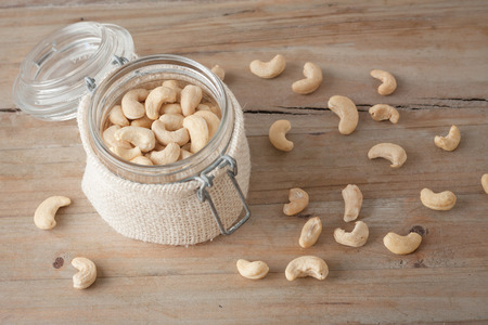 raw unsalted cashew nuts in glass jar on wooden rustic backgroundの写真素材