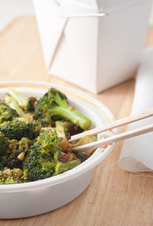 close up of chinese takeout consisting of broccoli in garlic sauce with chopsticksの写真素材