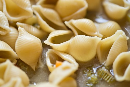 macro shot of pasta shells  in a pot with soupの写真素材