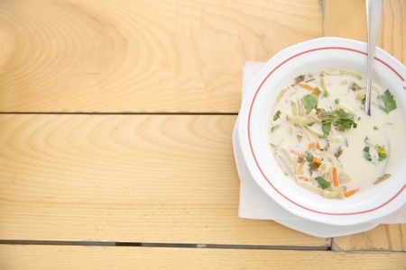 a white bowl of pickle soup on a wooden table outside, room for textの写真素材