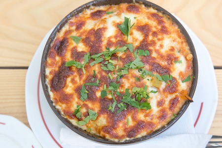 individual casserole baked dish with cheese, potatoes, vegetables and meat or fish, garnished with fresh parsley, top viewの写真素材