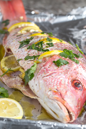 whole red snapper with lemon slices and parsleyの写真素材