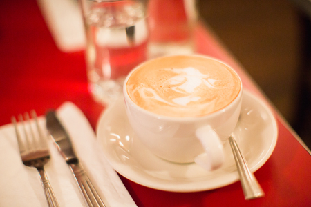 a cup of italian coffee with milk foam such as latte or cappuccino on red tableclothの写真素材