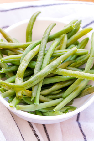 Cooked green string beans in a white bowl