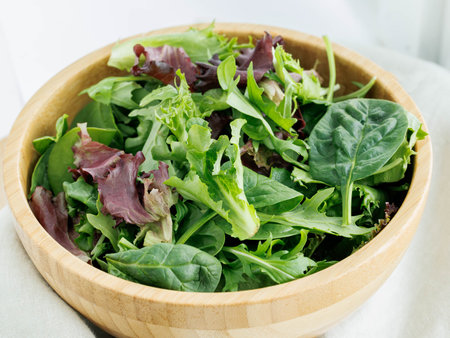 Fresh variety of salad greens in brown bowl view from aboveの写真素材