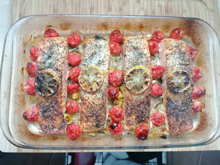 Baked salmon with lemon and cherry on a baking sheet in the ovenの写真素材