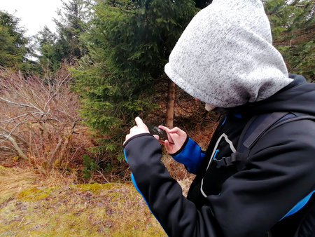 A young man is using a mobile phone in a forest in winterの写真素材