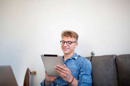 Young successful man writing a business plan for coffee shop using laptop computer and touch pad. Male skilled commercial real estate analyst working with net-book and digital tabletの写真素材