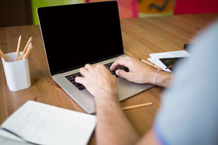 Businessman keyboarding on laptop computer with empty screen with copy space. Male marketing...