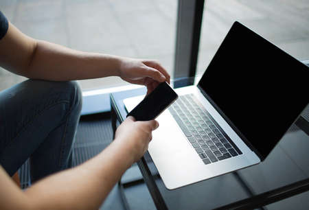 Closely man chatting on cell telephone, sitting at glass table with notebook with copy space screen....