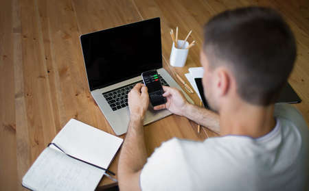 Specialist in generic real estate business plan using mobile phone with financial charts. Man trader...