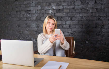 Woman distance worker chatting in social network on mobile phone during work on laptop computer....