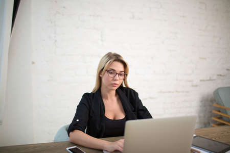 Businesswoman working on laptop computer, sitting in office interior. Female experienced broker...