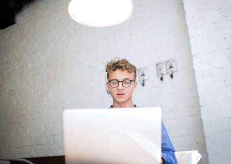Intelligent man business planning expert working on modern laptop computer, sitting with cup of...
