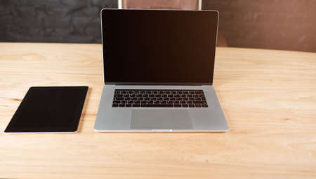 Touch pad and open laptop computer with blank copy space screen lying on a wooden table in modern...