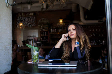 Young gorgeous woman college student talking via smartphone while sitting in coffee shop after...