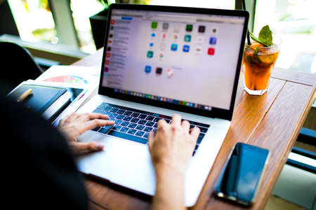 Closely business woman using applications on laptop computer, sitting in coffee shop during work break. Close up female advertiser working in internet via notebook during rest in cafeの写真素材