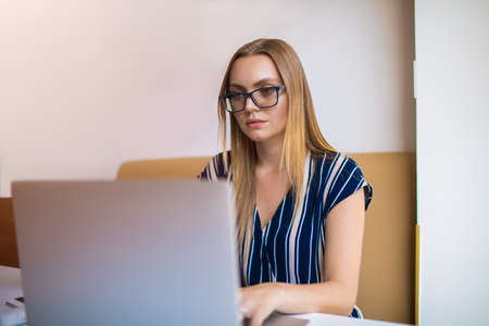 Young woman professional business plan writer reading article on laptop computer while sitting in...