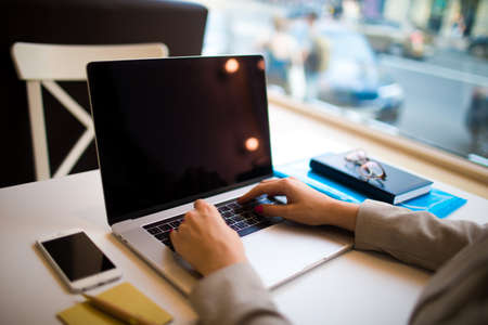 Woman entrepreneur working on laptop computer with empty screen background for advertising content...