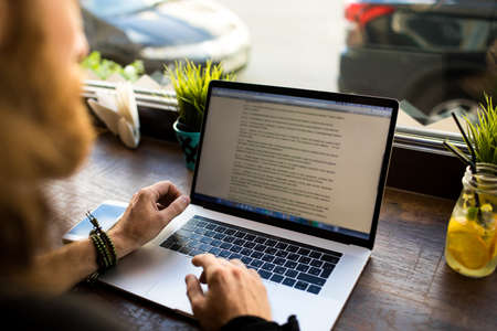 Man professional content writer working on web page via laptop computer while sitting in coffee shop...