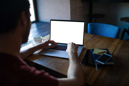 Man skilled publication specialist keyboarding on laptop computer with white empty screen background with copy space for advertising content, sitting in coworking space. Online education via netbookの写真素材