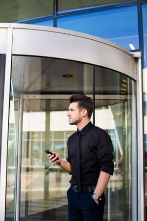 Man professional office worker waiting call on mobile phone while standing outdoors near company...