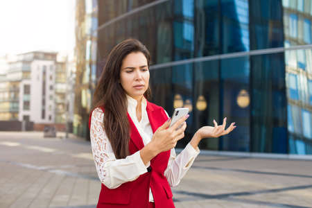 Upset woman lawyer received on mobile phone text message with bad news while standing outdoors...