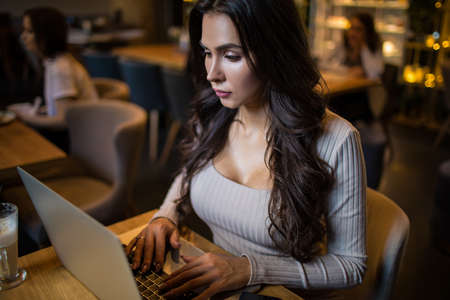Sexy woman using laptop computer while relaxing in coffee shop during recreation time in weekend....