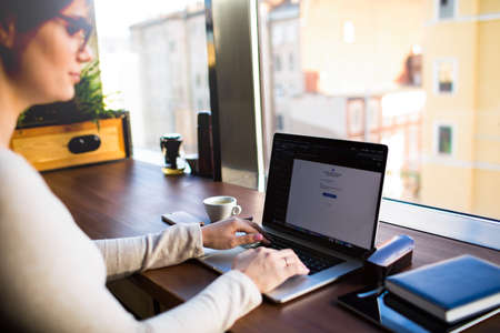 Woman business planning expert working on web site via modern pc laptop computer while sitting in restaurant during break at job. Female financier using applications on notebook device, resting in cafeの写真素材